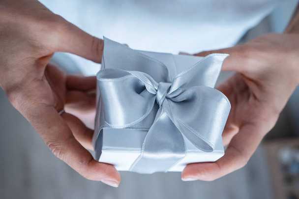 Femme mains tenant boîte cadeau avec arc blanc, gros plan
 - Photo, image