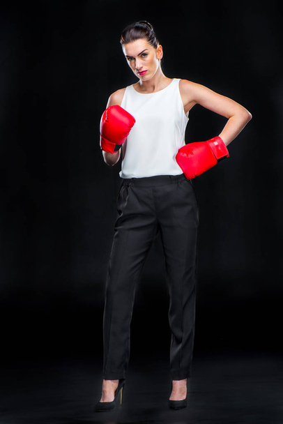 Full length portrait of young businesswoman in boxing gloves posing on black - Foto, immagini