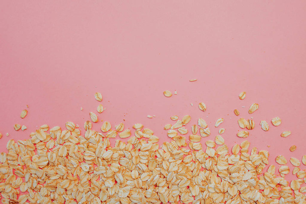 healthy diet, the concept. Grain oatmeal on a pink background. Oat flakes scattered - Foto, afbeelding