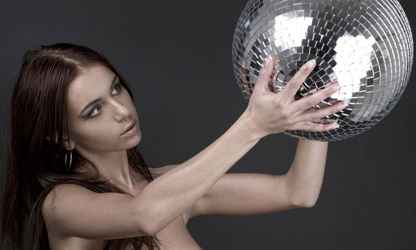 classical picture of muscular naked girl with glitterball over grey - Photo, image