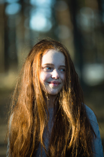 Cute teen girl with long bright red hair closeup portrait outdoors. - 写真・画像
