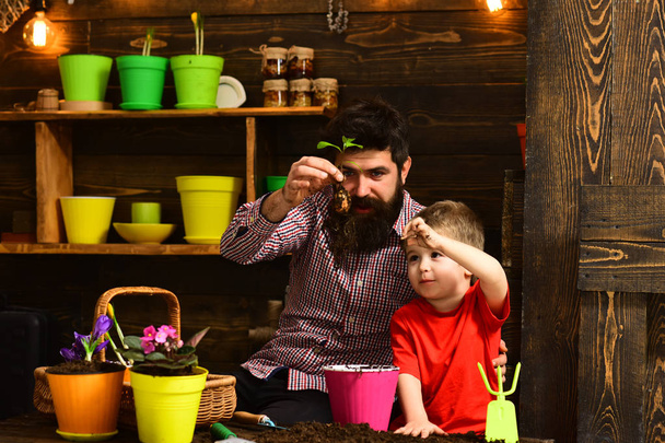 bearded man and little boy child love nature. happy gardeners with spring flowers. Family day. Greenhouse. Father and son. Flower care watering. Soil fertilizers. Natural gift - Fotografie, Obrázek