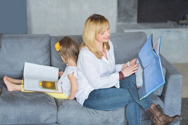 Mother and little daughter are playing, reading a book, sitting  - Foto, afbeelding