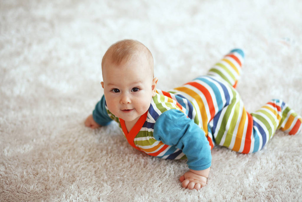 6 months baby lying down on a soft cozy carpet and looking at camera - Photo, Image