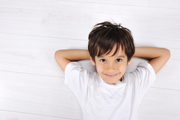 Little boy laying relaxed on white floor at home - Foto, imagen