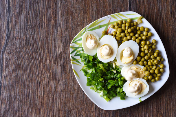 gekochte Eier unter Mayonnaise mit grünen Erbsen und grünen Zwiebeln. ein traditionelles russisches Gericht. - Foto, Bild