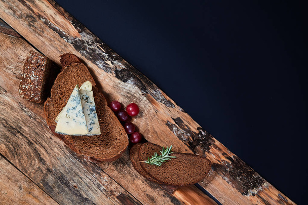 Cereal bread slices with aromatic blue cheese and grape berries on wooden planks - Photo, Image
