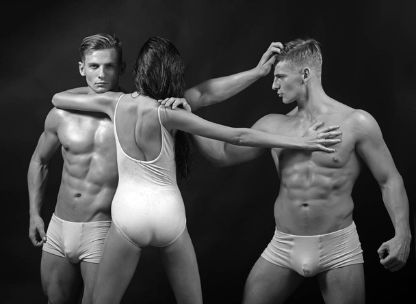 Twins men with muscular body and girl coach. Circus gymnasts at pilates or yoga training. Fitness and dieting. Flexibility in acrobatics. Gymnastic school and energy. Sport people or team work. - Фото, зображення