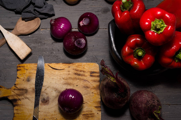 STILL LIFE OF RED PEPPERS WITH ONIONS ON A RUSTIC WOODEN TABLE - Photo, image