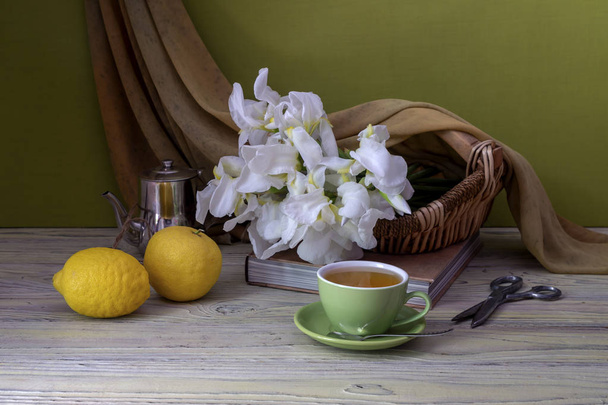 Букет білих ірисів, лимонів і чашки чаю крупним планом
 - Фото, зображення