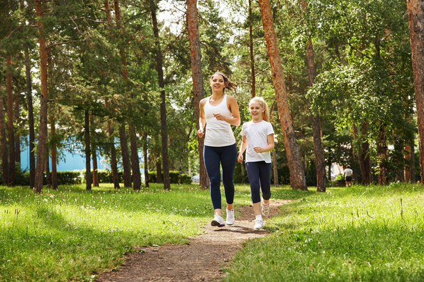 running mother and daughter. woman and child jogging in a park. outdoor sports and fitness family - Foto, Bild