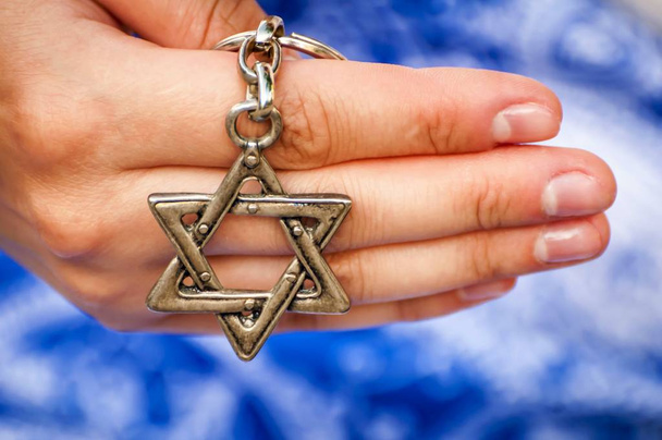 Geleneksel Yahudi sembolü David Yıldızı ile anahtarlık tutan genç bir kadının eli. Uluslararası Holokost anma günü için bir konsept imge, Holokost anıtı. - Fotoğraf, Görsel