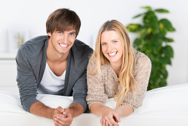 smiling young couple leaning on sofa - Foto, afbeelding