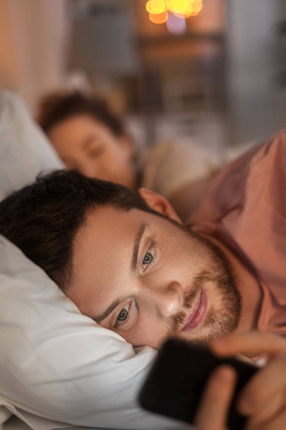 man using smartphone while girlfriend is sleeping - Zdjęcie, obraz