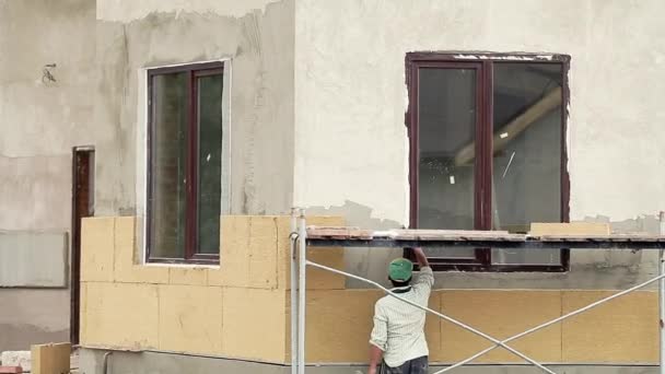 Працівник утеплює стіну зовнішньою будівлею
 - Кадри, відео