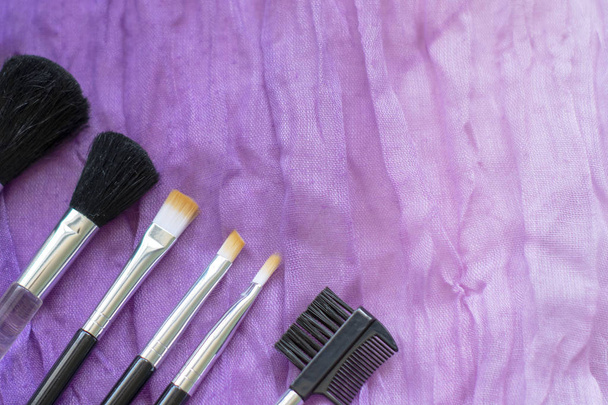 Professionele make-up cosmetische penselen op de achtergrond van verkruimelde golvende stof. Het concept van schoonheid en mode. Top uitzicht flat lag. Copyspace - Foto, afbeelding