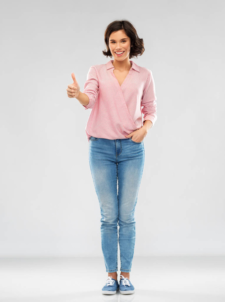 young woman in shirt and jeans showing thumbs up - Foto, Imagem