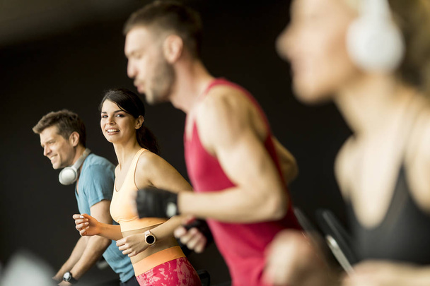 Groupe de jeunes qui courent sur des tapis roulants dans une salle de gym moderne
 - Photo, image