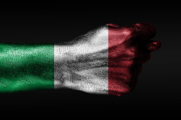 塗装されたイタリアの旗を持つ手は、イチジク、侵略の兆候、意見の相違、暗い背景の紛争を示しています. - 写真・画像