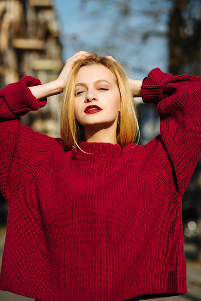 Mujer joven encantadora con labios rojos usando suéter de punto posando
  - Foto, Imagen