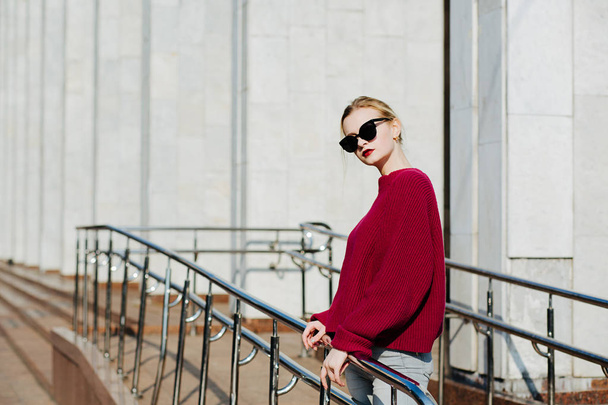 Modieuze blonde vrouw dragen trui en zonnebril wandelen  - Foto, afbeelding