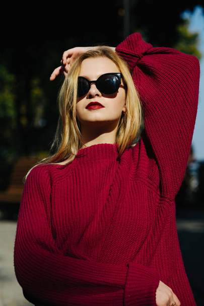 Stylish blonde model with red lips wearing black sunglasses posi - Foto, afbeelding