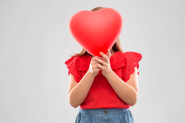 girl hiding behind red heart shaped balloon - Foto, imagen