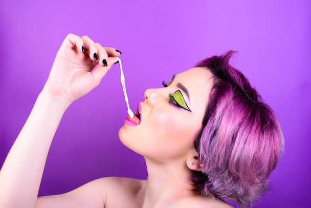 Girl stretches the cud. Sexy girl with short hair. Portrait of a woman with bright colored hair, all shades of purple. Beautiful lips and makeup. . Professional coloring. professional makeup. - Foto, afbeelding