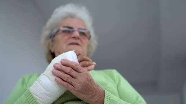 Alte Frau massiert ihre verletzte gebrochene Hand sitzend, cineastische dof - Filmmaterial, Video