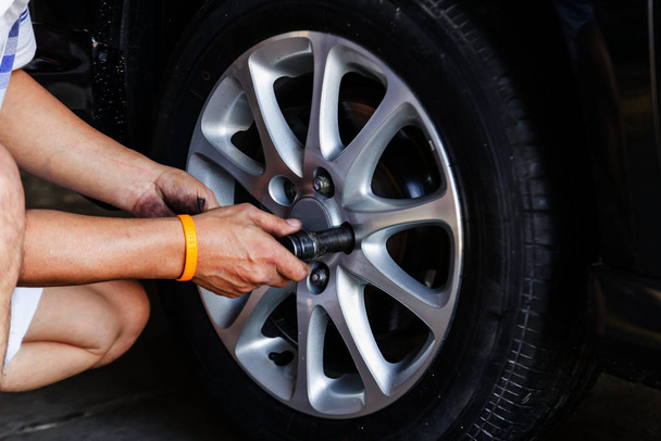 Replacing lug nuts by hand while changing tires on a vehicle. - Photo, image