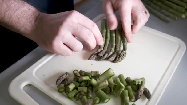 Chopping green asparagus on white cutting board - Footage, Video