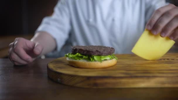 Şef burger dilimlenmiş çedar peyniri ekler ve pirişlet üzerine koyar, yavaş hareket burger pişirme, fast food restoran, 4k Uhd 60p Prores Hq 422 - Video, Çekim