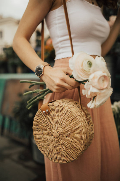 Fashionable young blogger girl holding a bunch of flowers at the flower market. Concept of blogging and street style fashion. Summer and spring outfit ideas. - Foto, Imagem