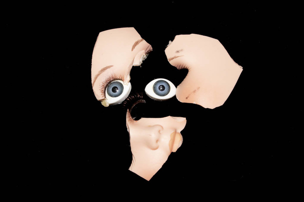 Σπασμένο πρόσωπο κεφάλι κούκλα στο μαύρο φόντο - Φωτογραφία, εικόνα