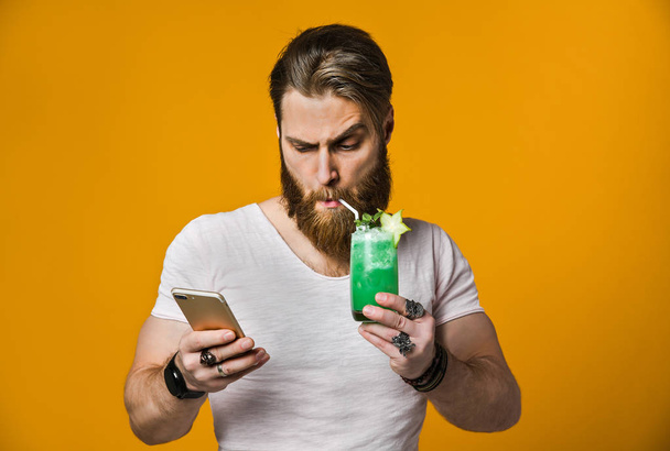 Young man holding a multicolored cocktail - Foto, Imagen