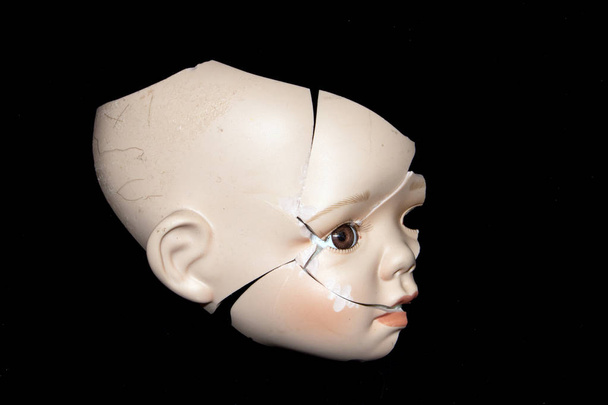 Cara de cabeça de boneca quebrada em fundo preto
 - Foto, Imagem