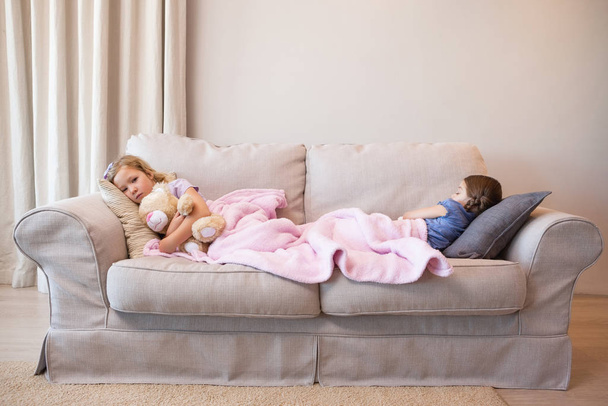 Θέα δύο νεαρά κορίτσια που κοιμούνται στον καναπέ στο σπίτι - Φωτογραφία, εικόνα