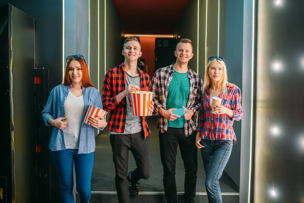 Teenagers with popcorn poses in cinema hall before the screening. Male and female youth in movie theater - Valokuva, kuva
