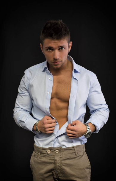 Confident, attractive young man with open shirt on muscular torso, ripped abs and pecs - Fotó, kép