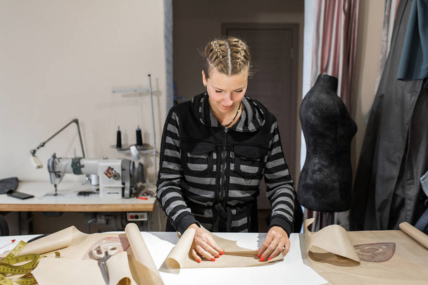 Uma jovem designer de roupas papel dobrado para um padrão. Fazendo
 - Foto, Imagem