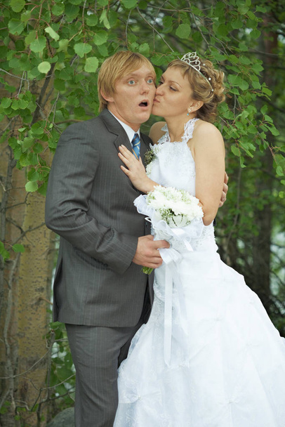 Amusing groom and the bride kiss secretly in bushes - Valokuva, kuva