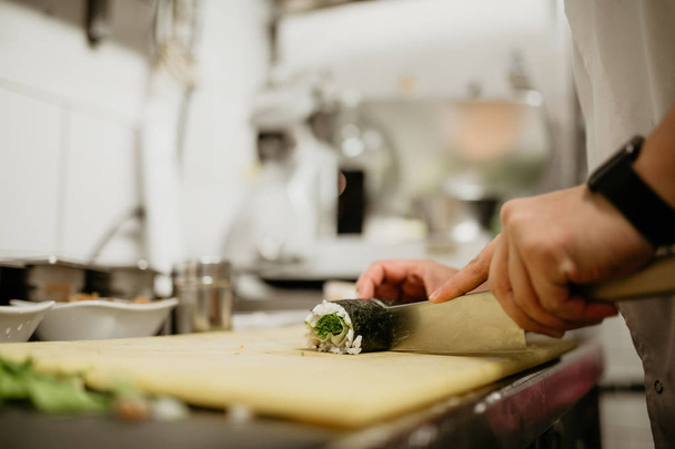 Een close-up shot van een chef-kok die sushi maakt. Concept van de Japanse culturele keuken, eten en gastvrijheid.   - Foto, afbeelding