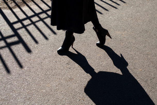 La sombra sobre el asfalto de las piernas femeninas
 - Foto, imagen