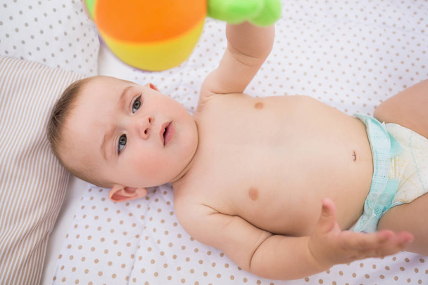 High angle view of adorable baby playing with toy in crib - Photo, image