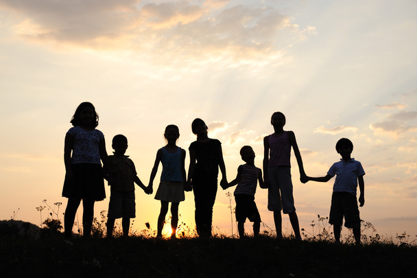Group of happy children playing on meadow, sunset, summertime - Fotó, kép