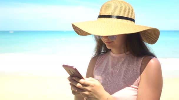 cestující žena, která používá telefon na pláži na letních prázdninách - Záběry, video
