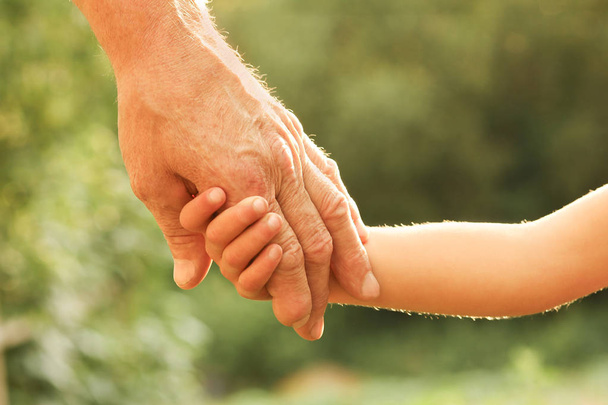 the parent holding the child's hand with a happy background - Photo, Image