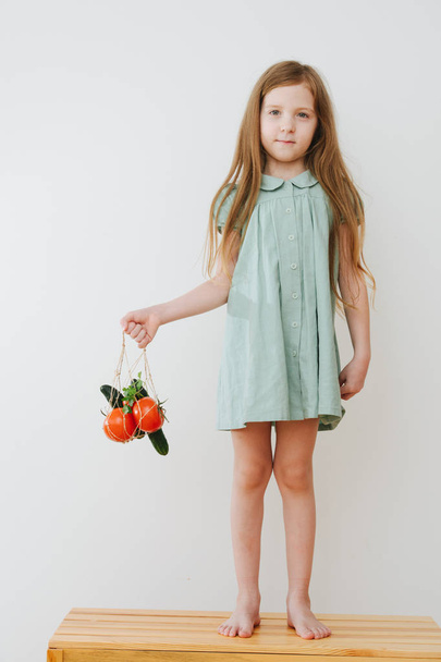 Little girl with vegetables in string bag - Foto, afbeelding