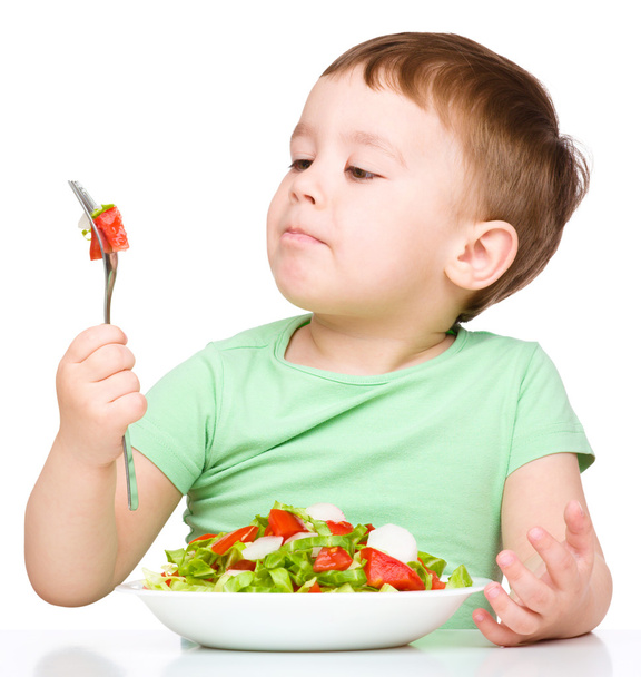 Cute little boy is eating vegetable salad - Fotoğraf, Görsel