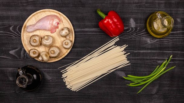 Fresh ingredients for cooking home-made fried noodles on a black rustic wooden table. Top view - Photo, Image